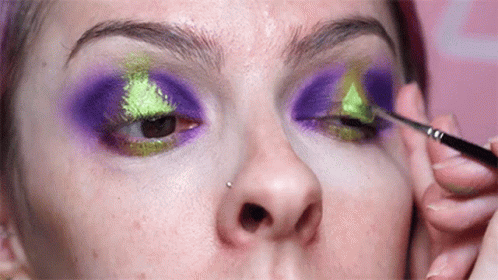 a woman with makeup that is covered in green and pink