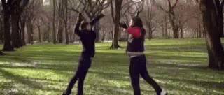 two people standing in the grass throwing frisbees