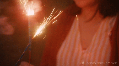 a girl is holding a sparkler in one hand and looking down