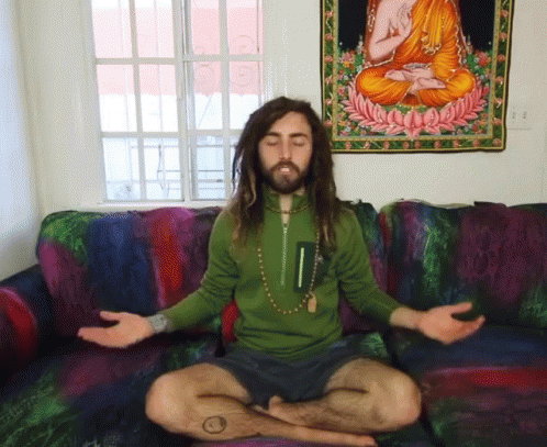 man in green shirt meditating in the middle of his couch
