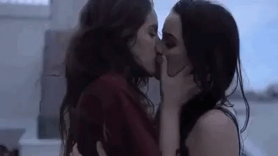 a woman that is kissing another woman in front of a building