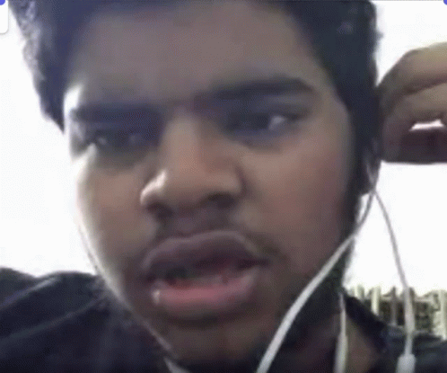 a young man with earbuds is covering his eyes and making faces