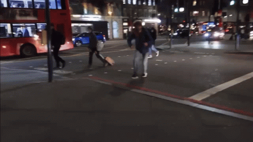 two people crossing a street with their luggage