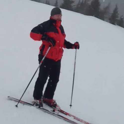 a man wearing skis standing at the top of a ski slope