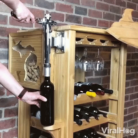 someone's hand is reaching for a bottle of wine in a rack