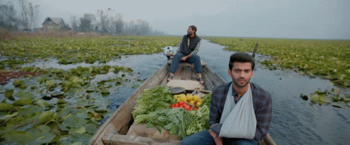 two people on a boat on an open area with crops