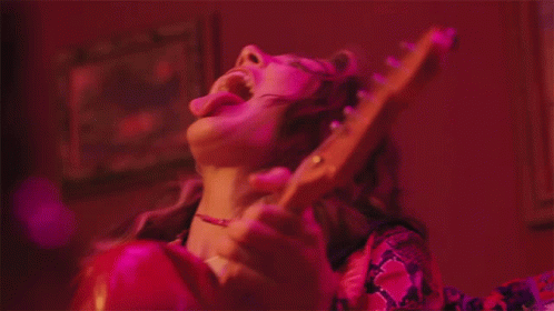 a woman with a guitar playing in purple light
