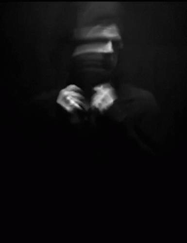 blurred image of man wearing a hat and holding his hands near his face