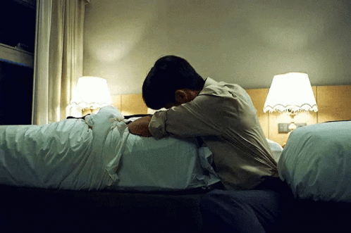 a person laying on a bed near lamps