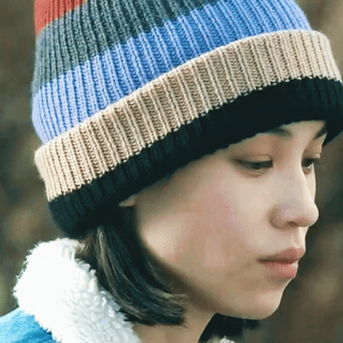 a woman is wearing a multicolored winter hat