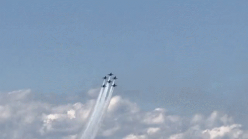 four airplanes are flying in the sky leaving smoke trails