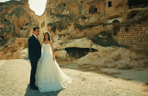 the bride and groom standing next to each other near some cliffs