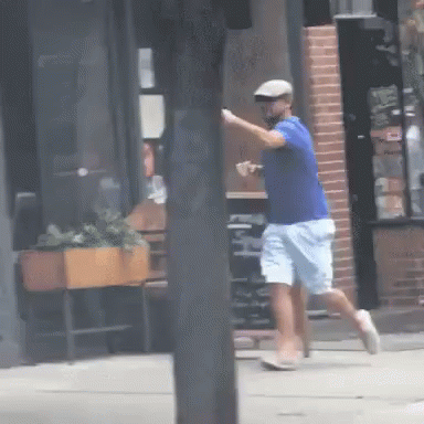 a boy is swinging a bat on a sidewalk