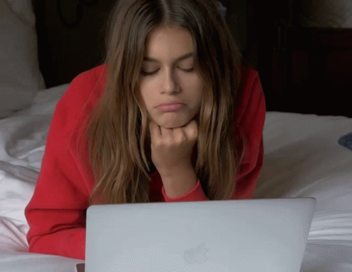 a woman sitting on her bed with a laptop