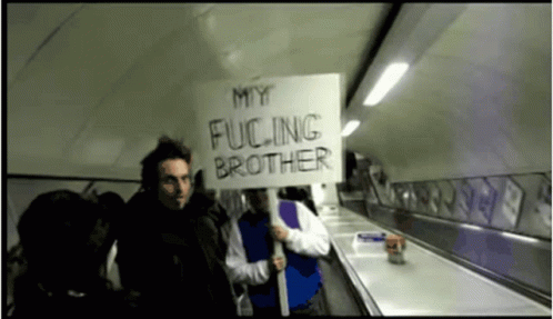 a man holding a sign that says my ing brother