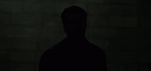 silhouette of man with cell phone in dark area