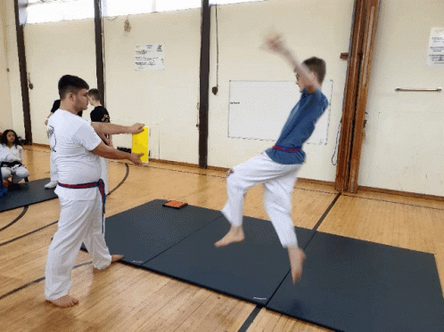 two people practice karate in an indoor gym