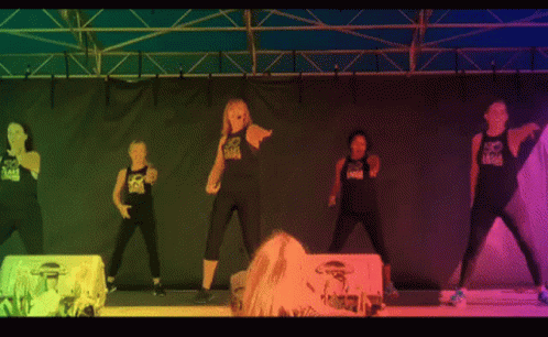 four models on stage performing a routine with bright lights behind them