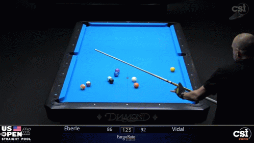a man standing in front of a table with a pool cue