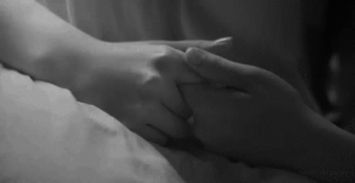 an individual holding hands on top of a bed