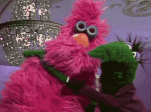 two stuffed animals from sesame street characters, one being hugged by another