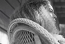 a man with long hair in a fur lined chair