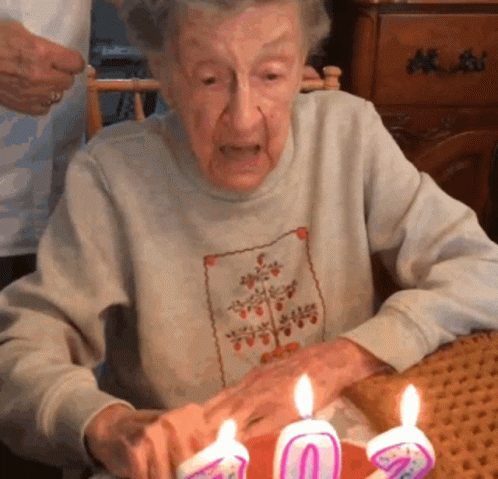 an old woman holding up some lit candles