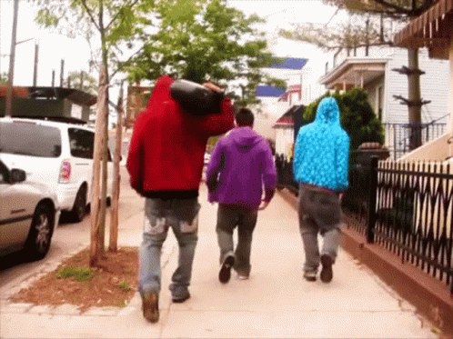 three people in winter jackets walking on the sidewalk