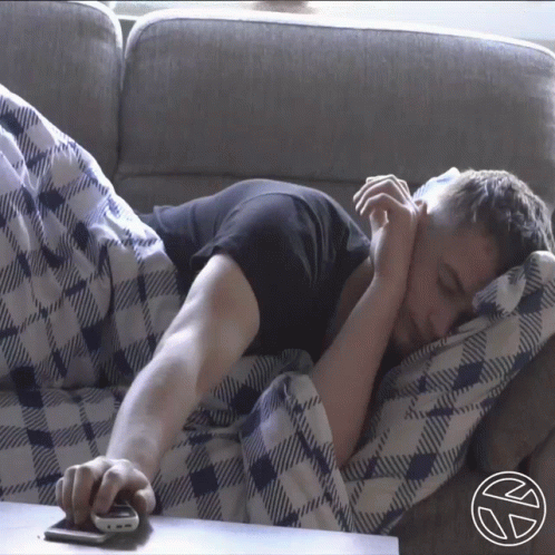 a man sleeping on the couch while holding a remote