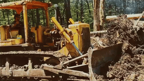 a bulldozer parked in the dirt next to trees