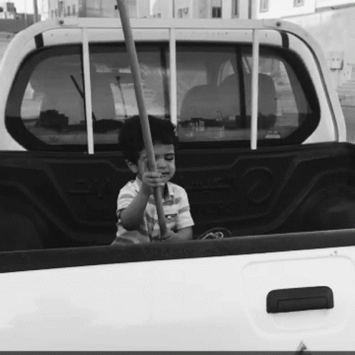 black and white po of boy sitting in bed of truck