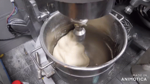 the machine is mixing blue powder into a large bowl