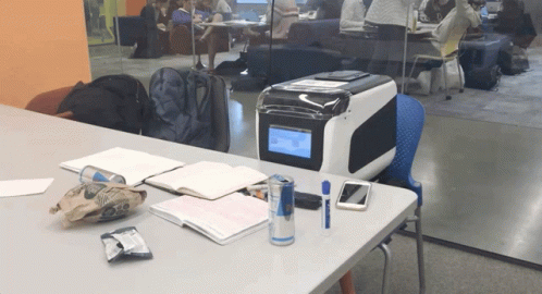 an office desk with a printer on it with people in the background