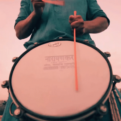 an indian man holds a drum in front of his face