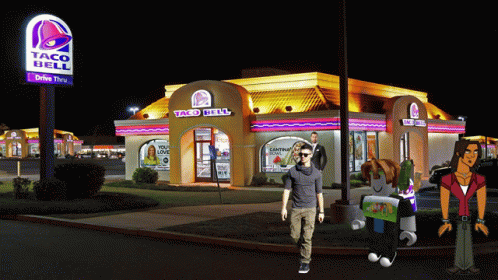 three people outside a taco bell restaurant at night