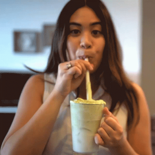 woman making silly face while drinking milkshake