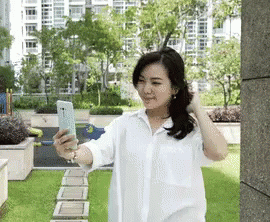 a woman taking pictures of herself with her cell phone