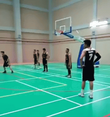 a group of guys playing basketball inside a gym