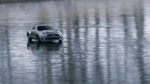 a car in water on the beach with reflections