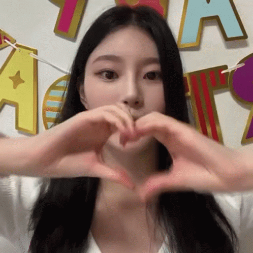 an animated po of a young woman making a heart sign with her hands