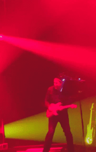 a male in a black shirt is playing a guitar