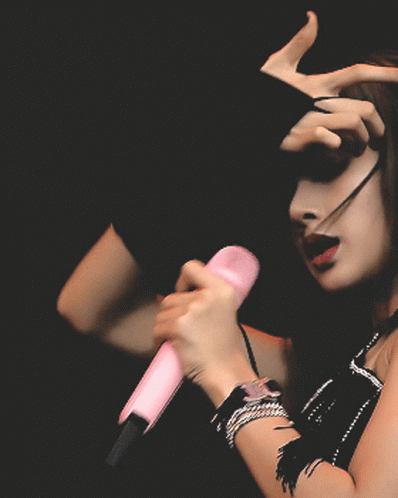 a woman with her hands on top of her head and a microphone in her other hand