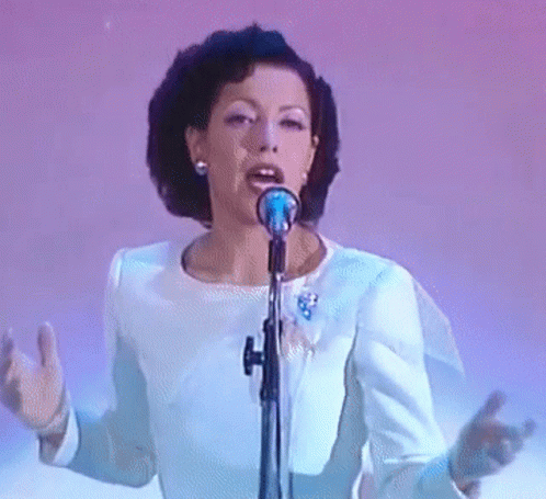 woman with dark hair singing into a microphone