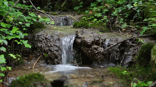 there is an old rock and water fall near a stream