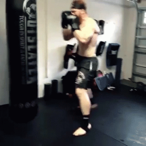 a man in a gym kicking bags near some punching equipment