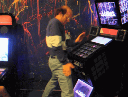 a man in overalls with an arm outstretched working on an electronic game