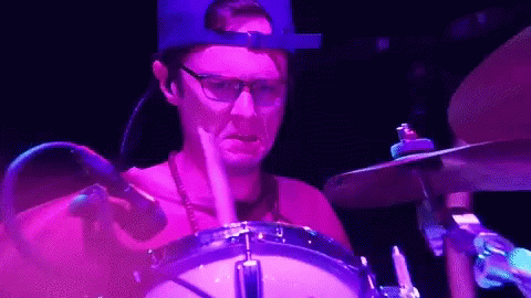 the drummer is wearing a red hat and making a rock band look mean