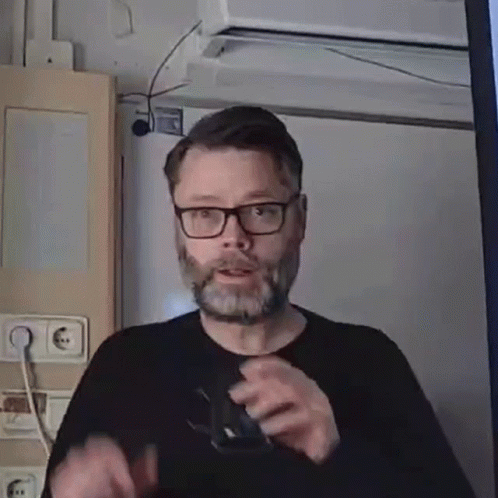 a man with glasses and a beard, in front of a video camera