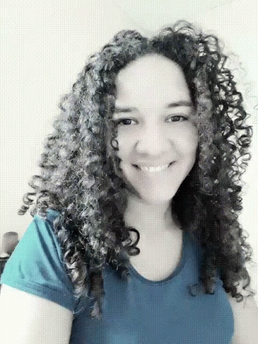 a woman with curly hair wearing a brown shirt