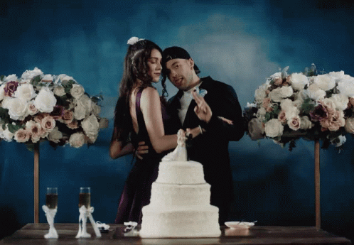 a couple standing in front of a wedding cake